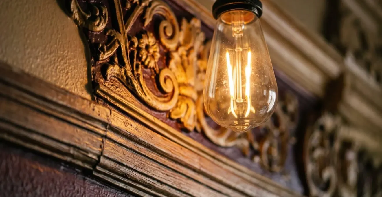 Close-up macro shot of a vintage-style LED light bulb emitting warm 2700K light, revealing rich wood tones and period paint colors