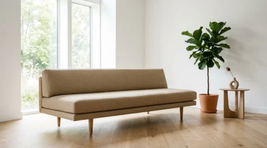 Modern low-profile sofa with raised wooden legs in a minimalist living room with natural light