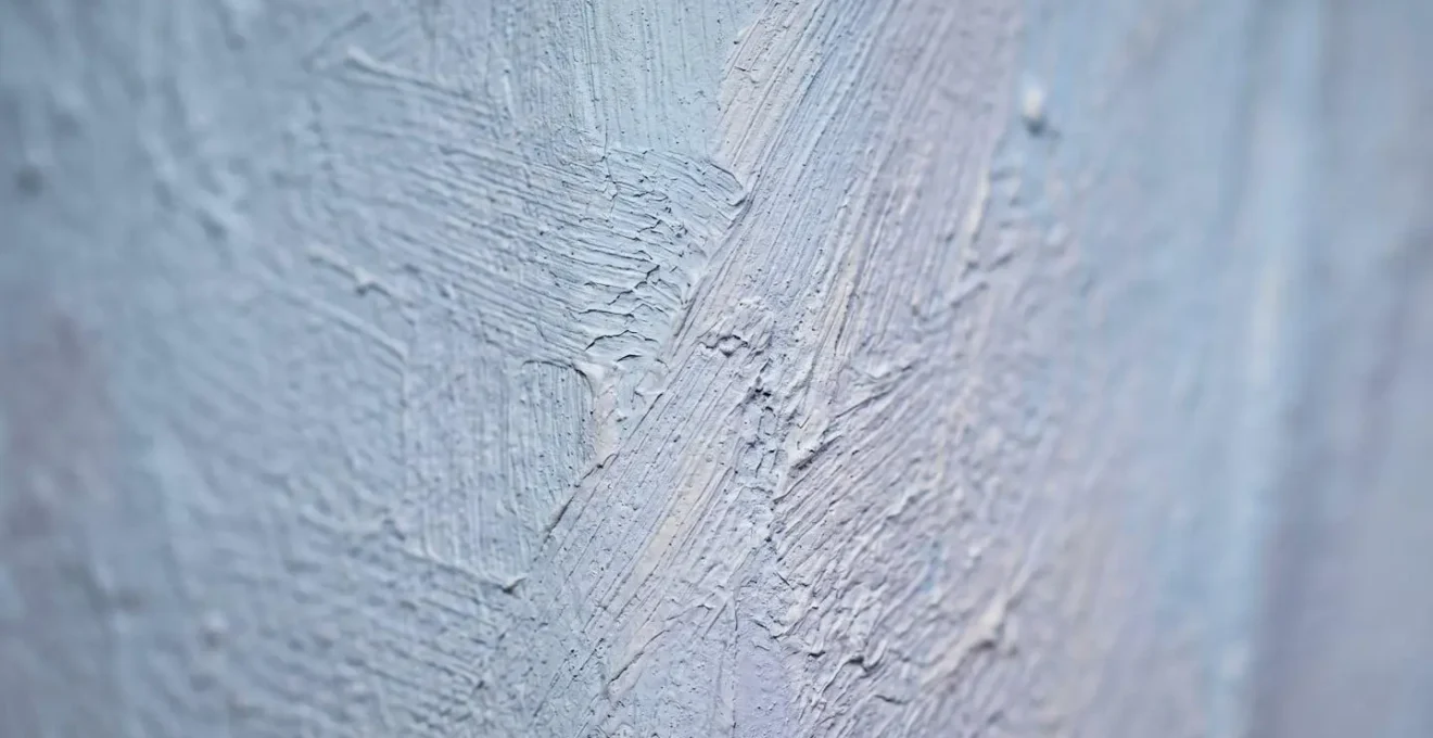 Close-up macro view showing pale blue paint sample displaying different undertones under varying light conditions with subtle texture details