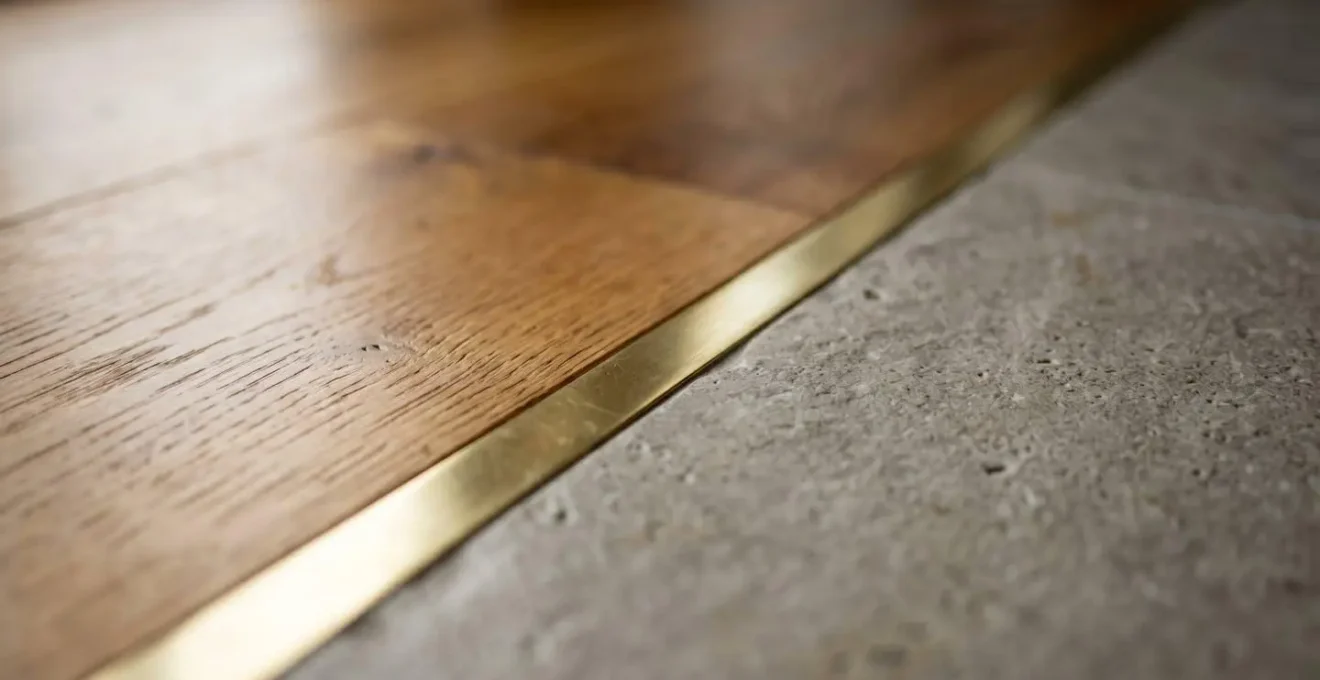 Close-up detail of elegant brass inlay creating seamless transition between wood and tile flooring
