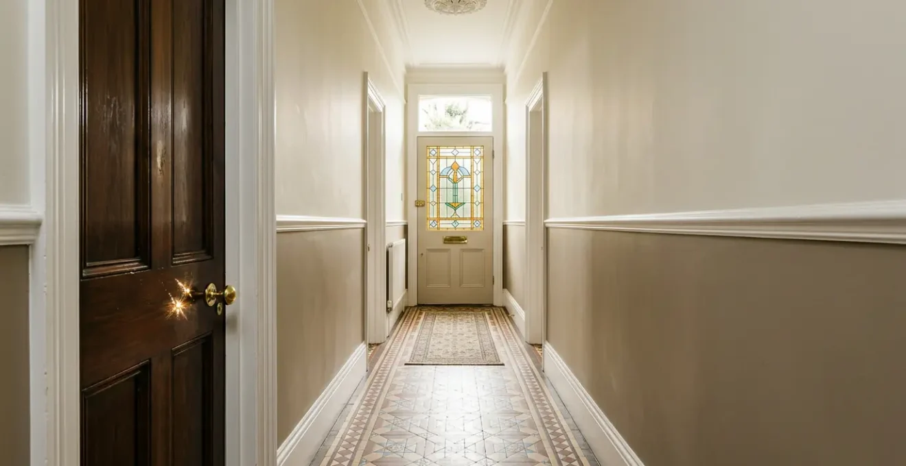 Elegant Victorian foyer with original encaustic floor tiles, brass door hardware, and period ceiling details bathed in warm natural light